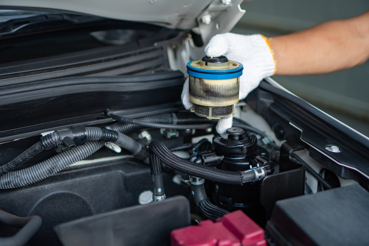 Auto mechanic replaces a car's fuel filter.